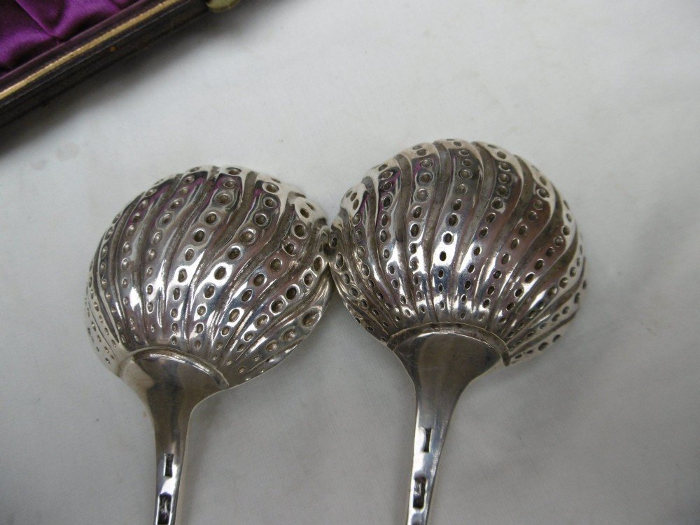 A pair of Georgian sterling silver ladles with Onslow pattern scroll handles and shell-shaped bowls resting inside a velvet-lined presentation box. View V