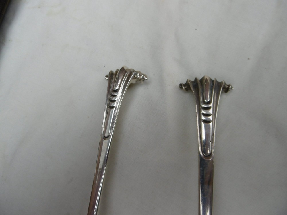 A pair of Georgian sterling silver ladles with Onslow pattern scroll handles and shell-shaped bowls resting inside a velvet-lined presentation box. View VI