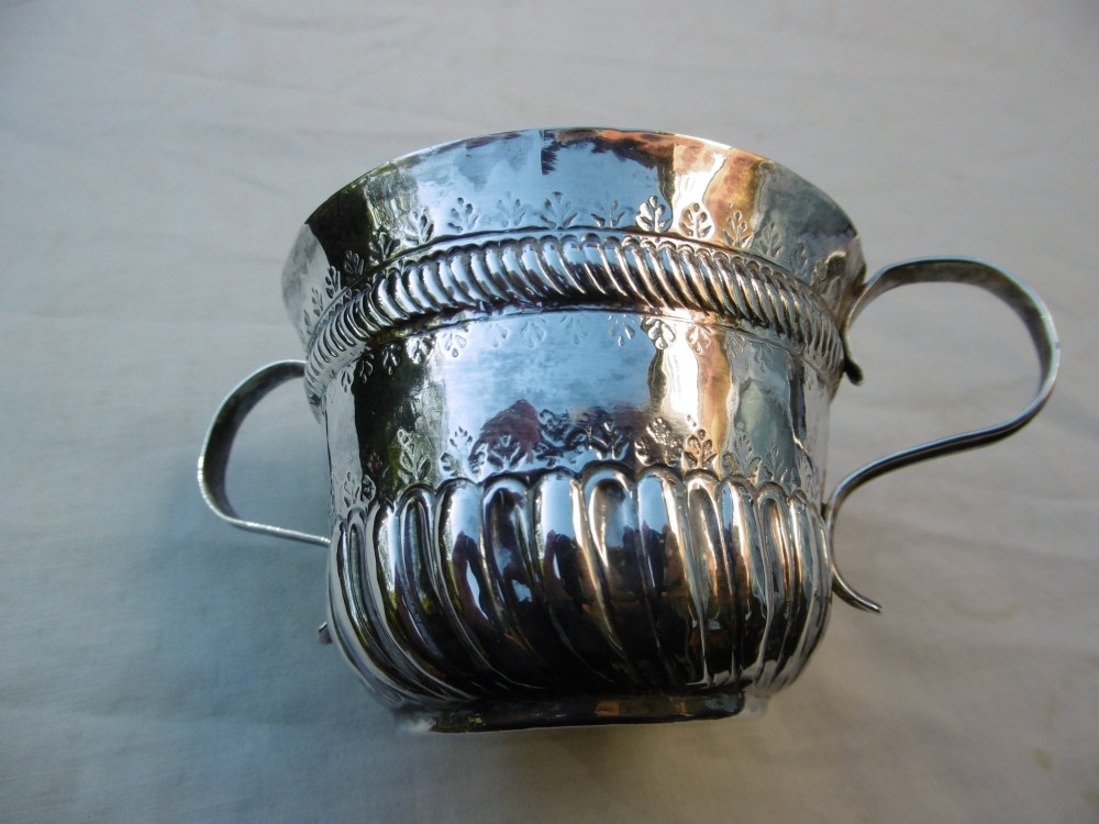 A George I Britannia standard silver porringer with twin scroll handles, fluted lower body decoration, and gadrooned banding. View III
