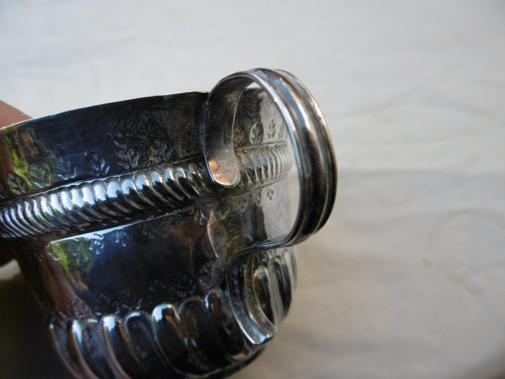 A George I Britannia standard silver porringer with twin scroll handles, fluted lower body decoration, and gadrooned banding. View IV