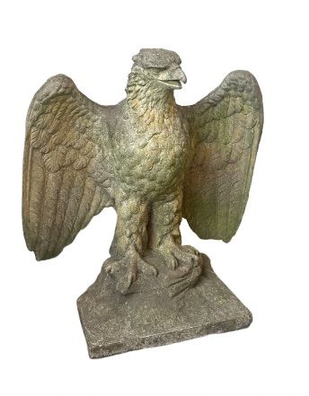 A weathered composite stone eagle sculpture with spread wings mounted on a square plinth base.