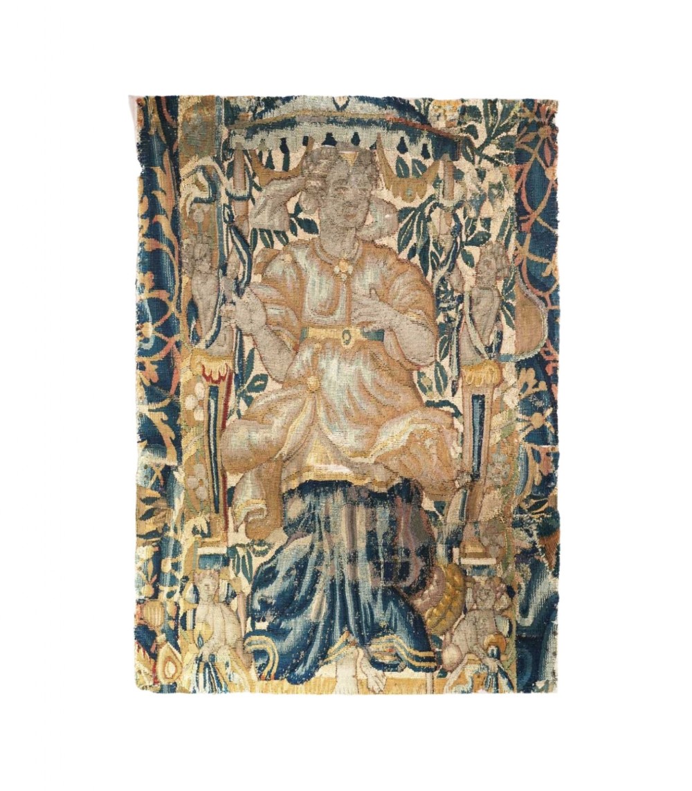 A 17th-century Flemish tapestry fragment depicting a seated figure under an architectural canopy woven in blue, ochre, and cream tones.
