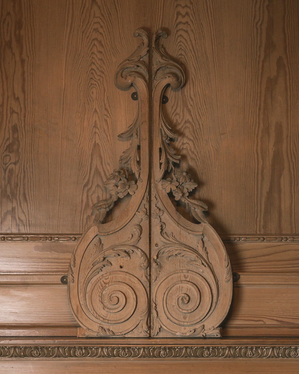 A symmetrical pair of hand-carved 18th-century limewood wall appliques featuring acanthus foliage, flower blossoms, and C-scroll details.