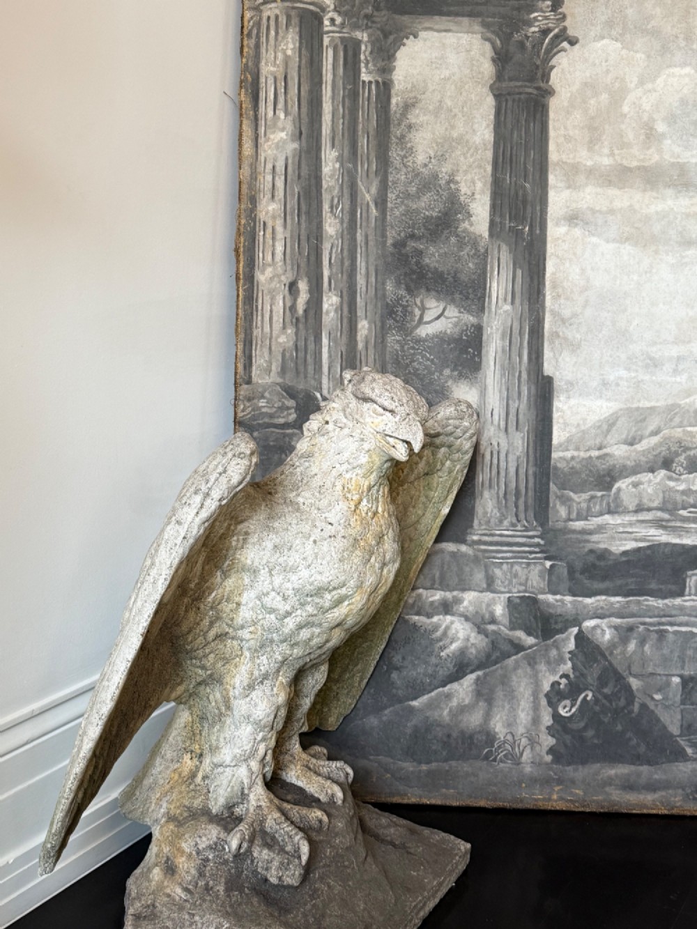 A weathered composite stone eagle sculpture with spread wings mounted on a square plinth base. View III