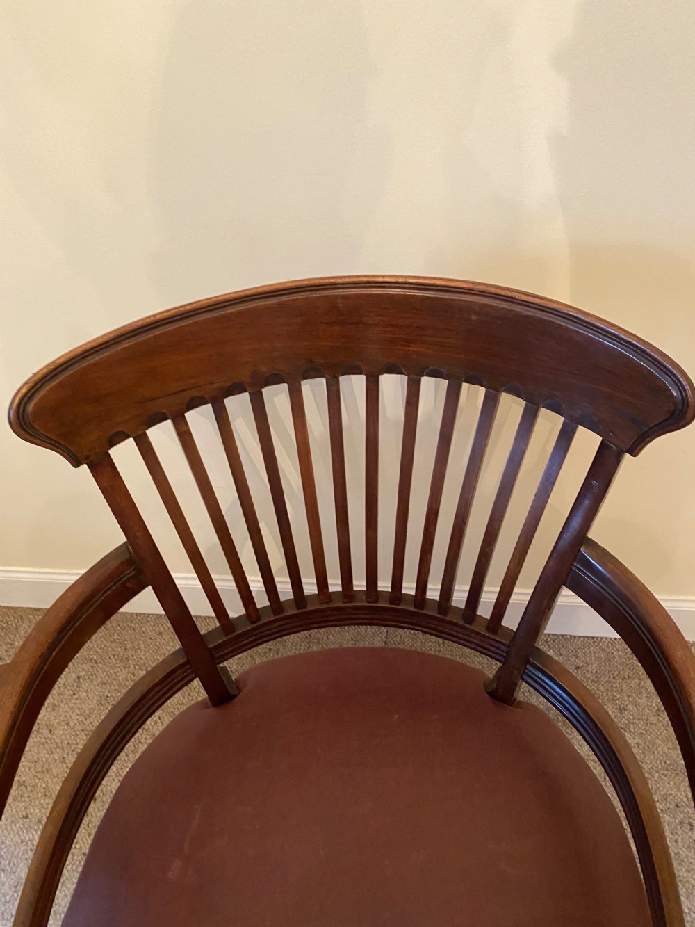A pair of mahogany club armchairs featuring vertical slat backrests, curved arms with turned supports, and reddish-brown leather upholstered seats with stud detailing. View IV