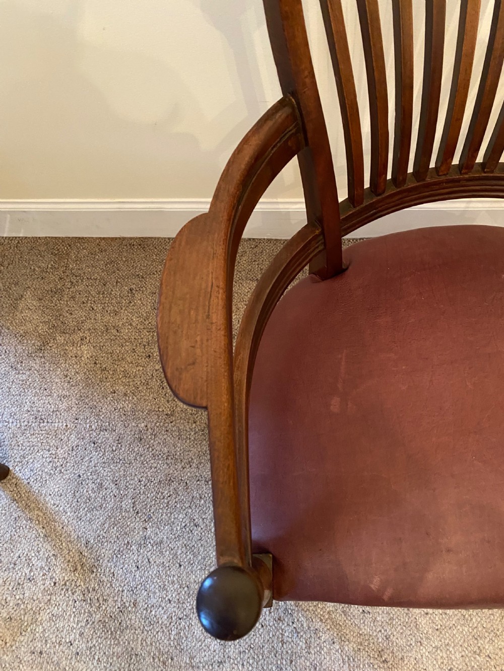 A pair of mahogany club armchairs featuring vertical slat backrests, curved arms with turned supports, and reddish-brown leather upholstered seats with stud detailing. View V