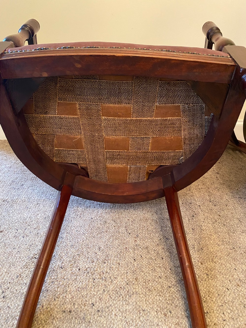 A pair of mahogany club armchairs featuring vertical slat backrests, curved arms with turned supports, and reddish-brown leather upholstered seats with stud detailing. View VI