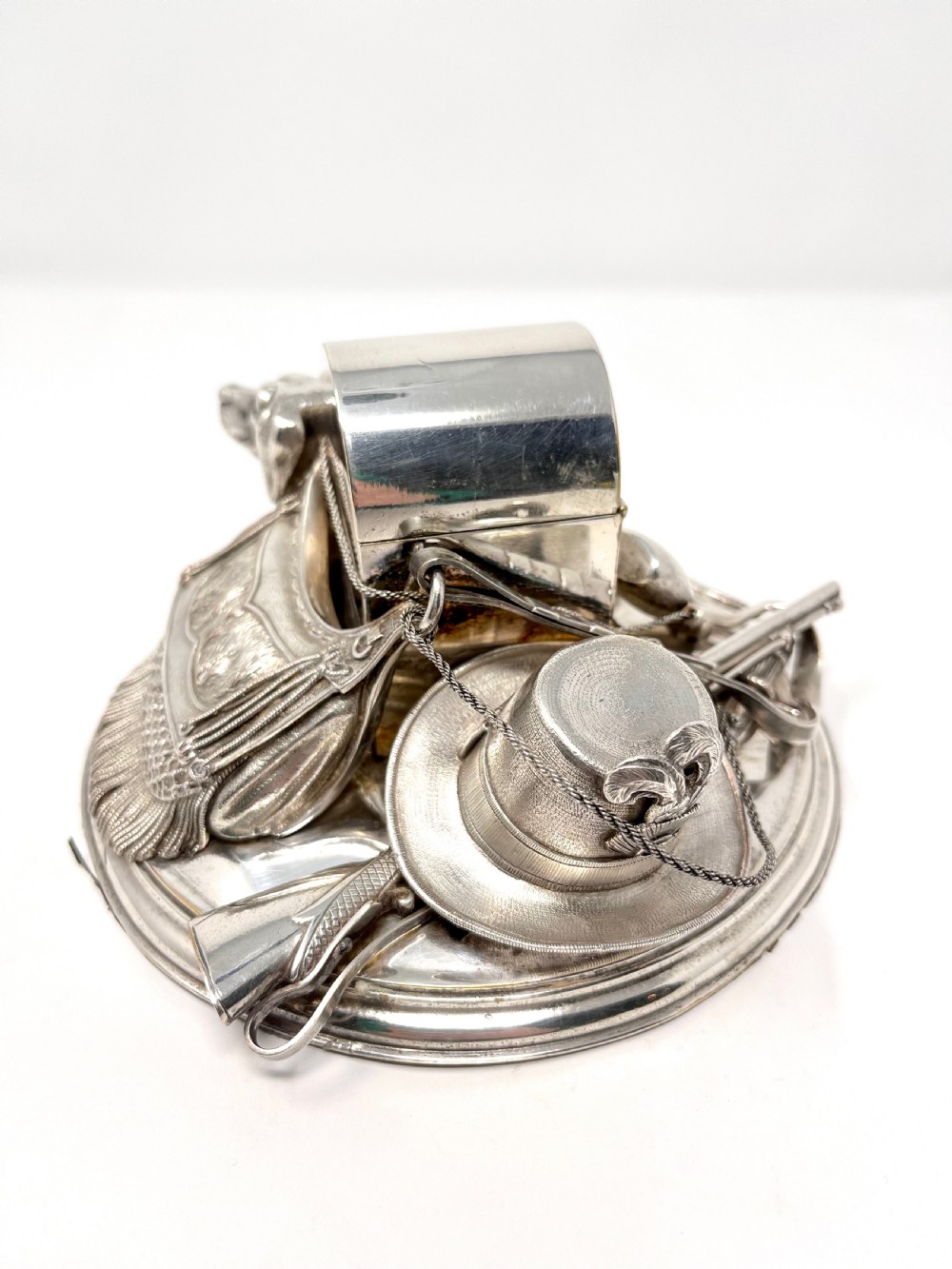 A Victorian silver-plated desk inkstand featuring a sculpted reclining hunting hound next to a game bag and domed ink container on a circular stepped base. View III