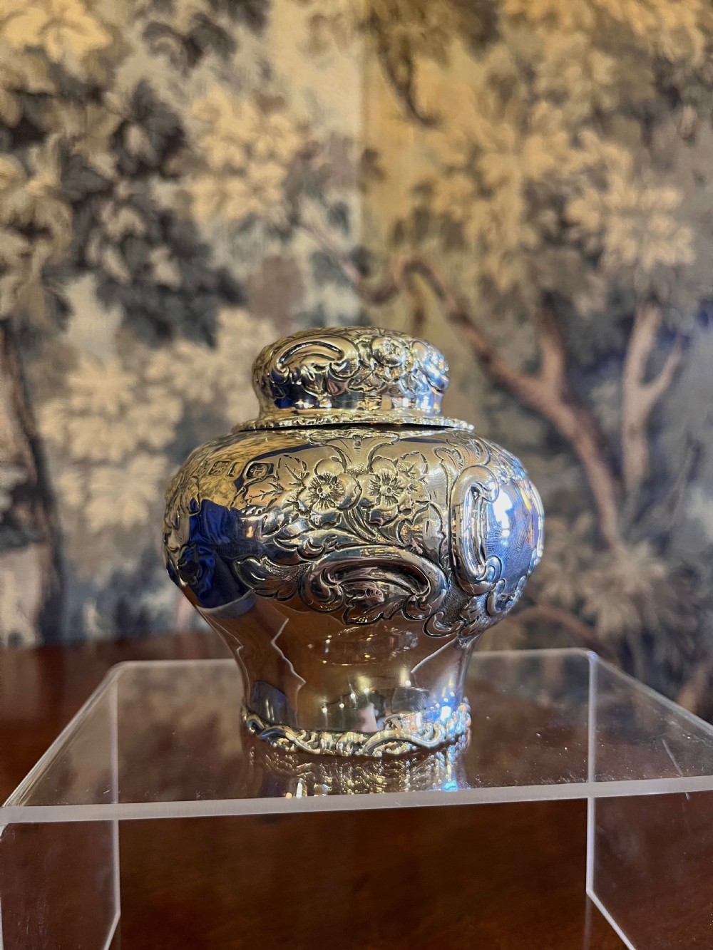 A bulbous antique silver tea caddy featuring hand-chased floral repousse decoration, visible hallmarks, and a fitted domed cap. View II