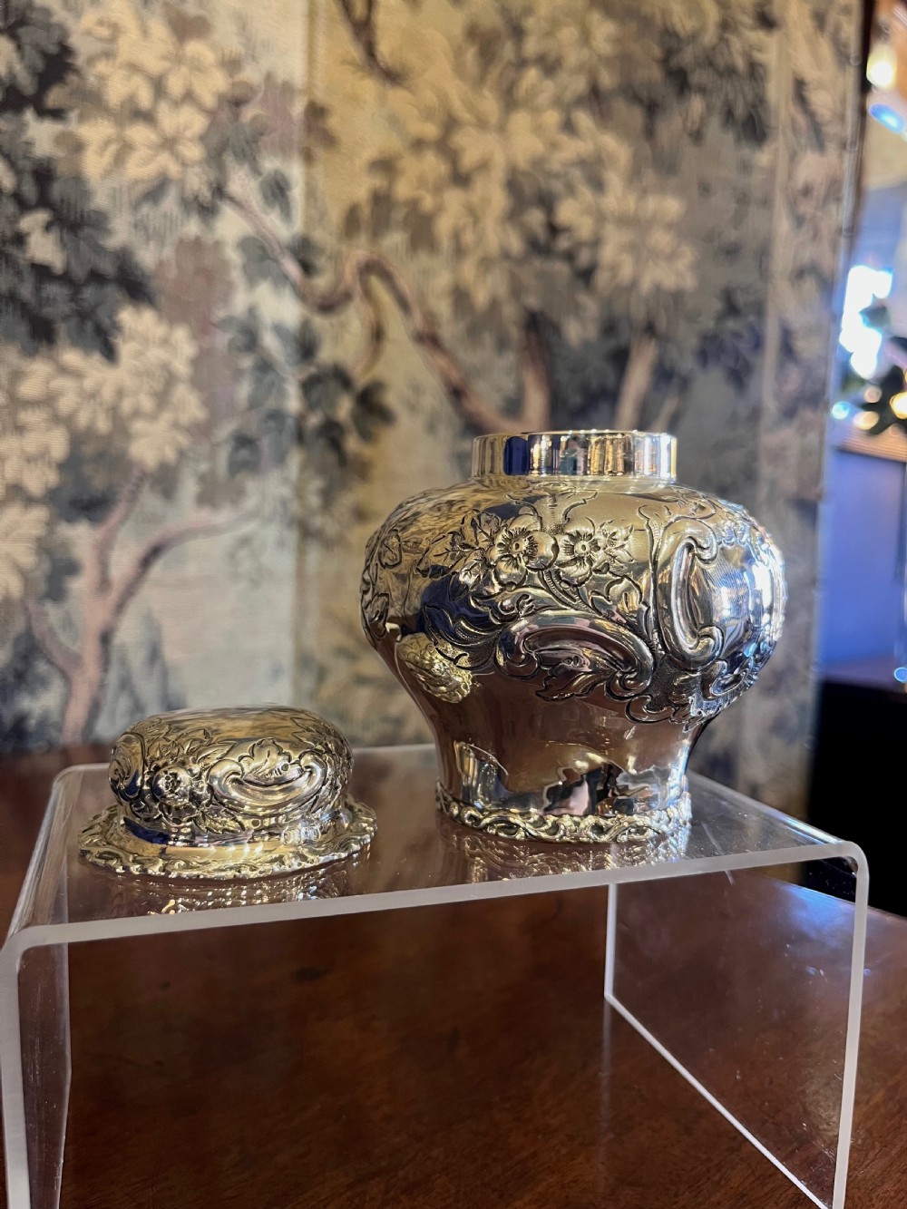 A bulbous antique silver tea caddy featuring hand-chased floral repousse decoration, visible hallmarks, and a fitted domed cap. View IV