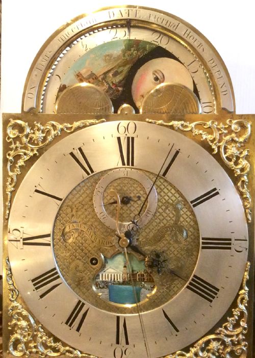 fig 1. An 18th-century mahogany longcase clock featuring a swan-neck pediment, an arched dial, and flame mahogany door.