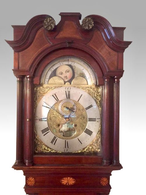 fig 3. An 18th-century mahogany longcase clock featuring a swan-neck pediment, an arched dial, and flame mahogany door.