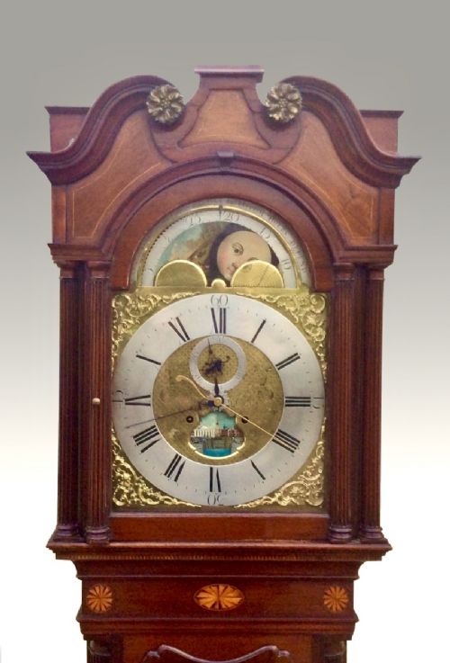 fig 4. An 18th-century mahogany longcase clock featuring a swan-neck pediment, an arched dial, and flame mahogany door.