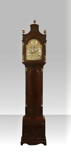 fig 2. A George III mahogany longcase clock featuring an arched brass dial with spandrels, fluted Corinthian columns, and a pagoda hood topped with brass finials.