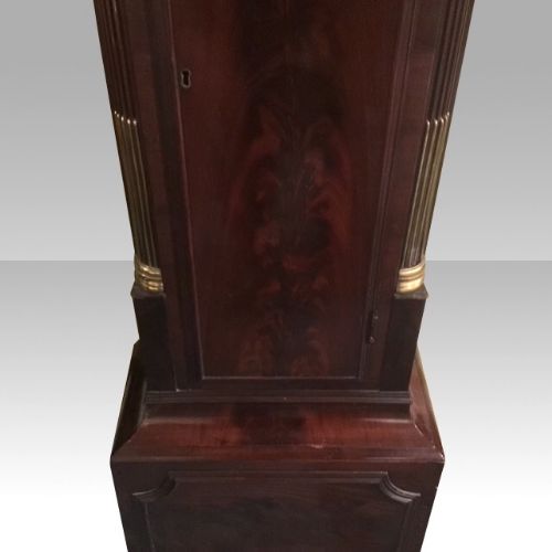 fig 4. A George III mahogany longcase clock featuring an arched brass dial with spandrels, fluted Corinthian columns, and a pagoda hood topped with brass finials.