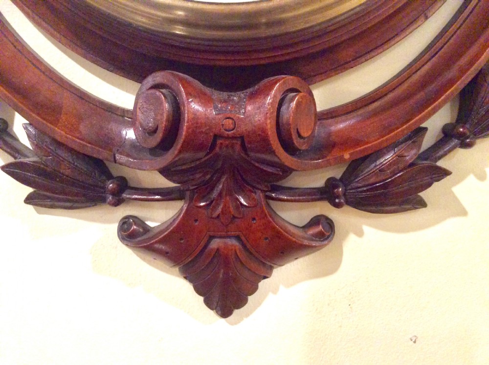 A carved mahogany Victorian aneroid wall barometer featuring a circular dial with weather markings framed by carved leaf motifs and scrollwork. View IV