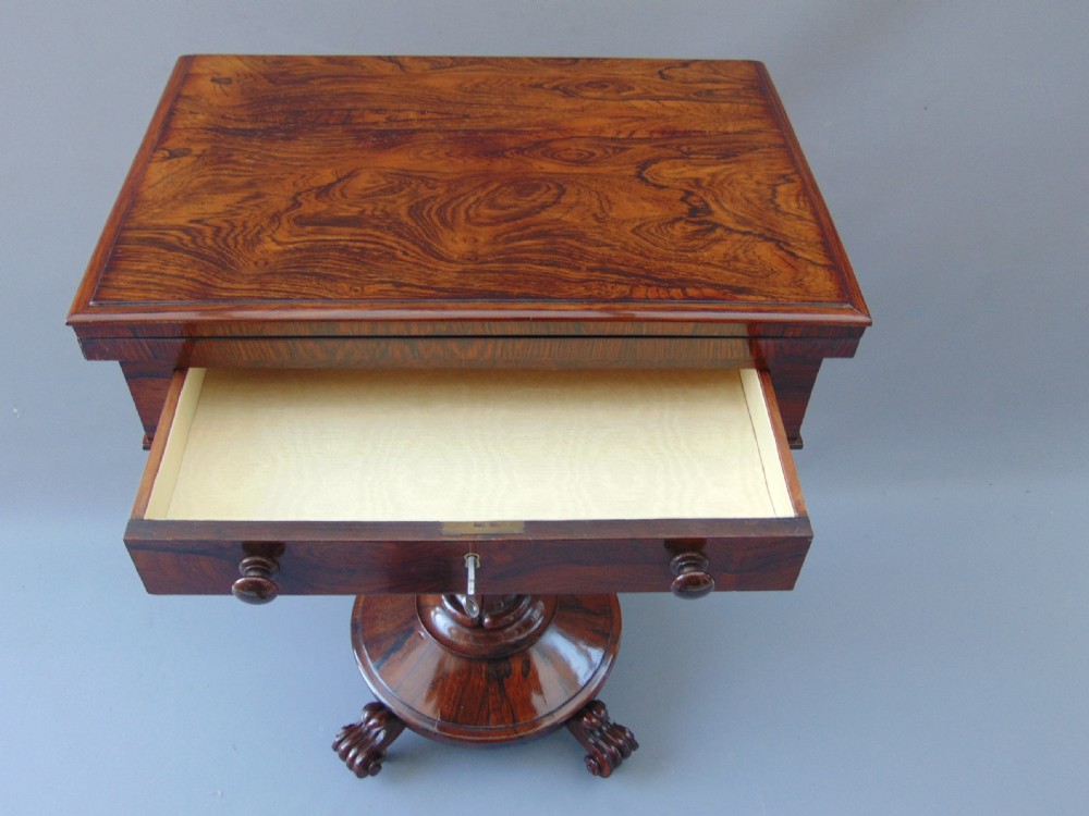 A William IV rosewood sewing and games table with a fold-over top, single drawer, suspended cream fabric work basket, and turned pedestal base with scroll feet. View VIII