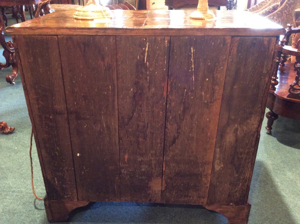 A Georgian walnut kneehole desk featuring a long top drawer above a central recessed cupboard flanked by six small side drawers, resting on bracket feet. View VII