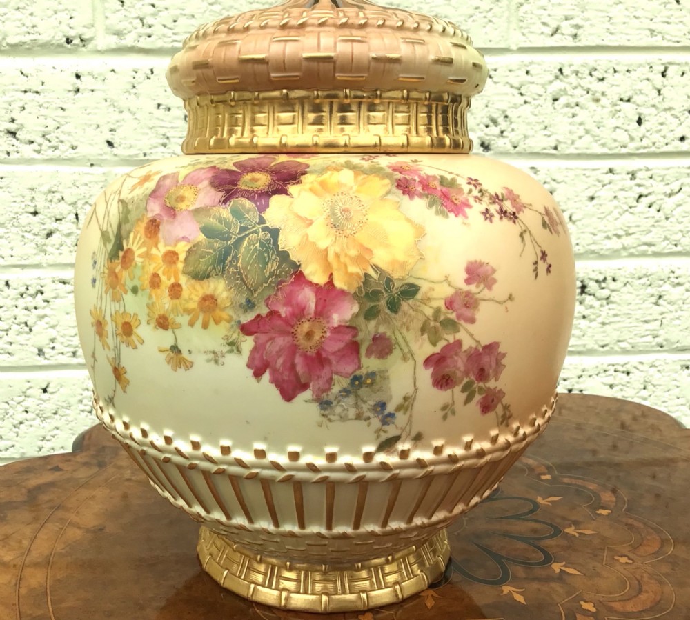 A globular Royal Worcester blush ivory pot pourri vase featuring hand-painted floral motifs, basketweave relief detail, and a pierced gilded lid. View VI