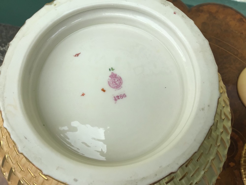 A globular Royal Worcester blush ivory pot pourri vase featuring hand-painted floral motifs, basketweave relief detail, and a pierced gilded lid. View VIII