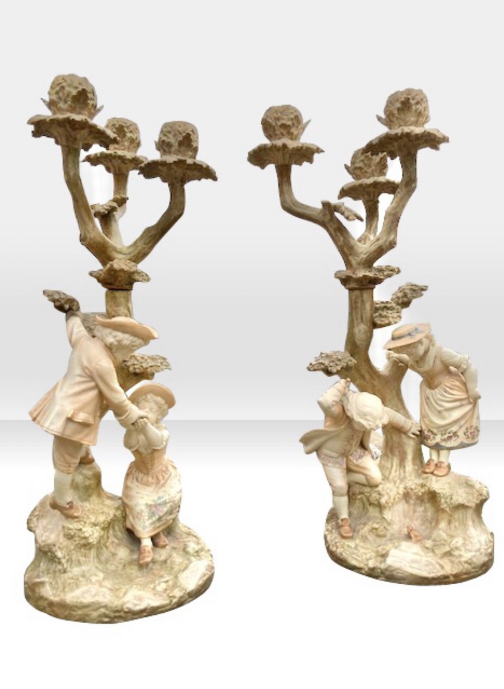 Pair of late 19th-century Royal Worcester blush ivory porcelain candelabra with tree-trunk candle branches and figures of children around the base.