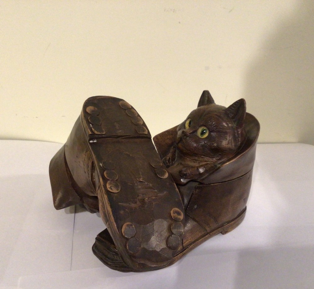 A pair of hand-carved dark brown wood inkwells shaped like cats sitting inside boots with green glass eyes. View III