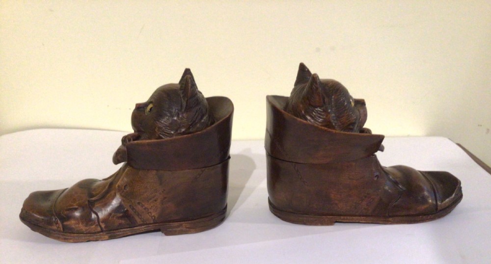 A pair of hand-carved dark brown wood inkwells shaped like cats sitting inside boots with green glass eyes. View V