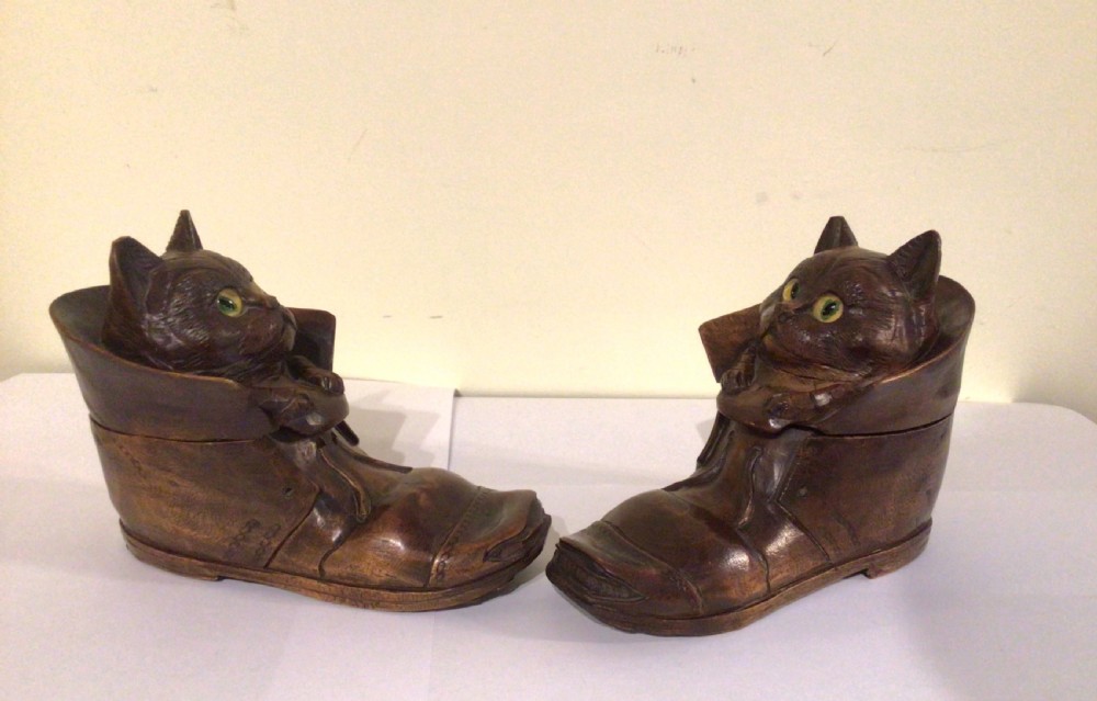 A pair of hand-carved dark brown wood inkwells shaped like cats sitting inside boots with green glass eyes. View VI