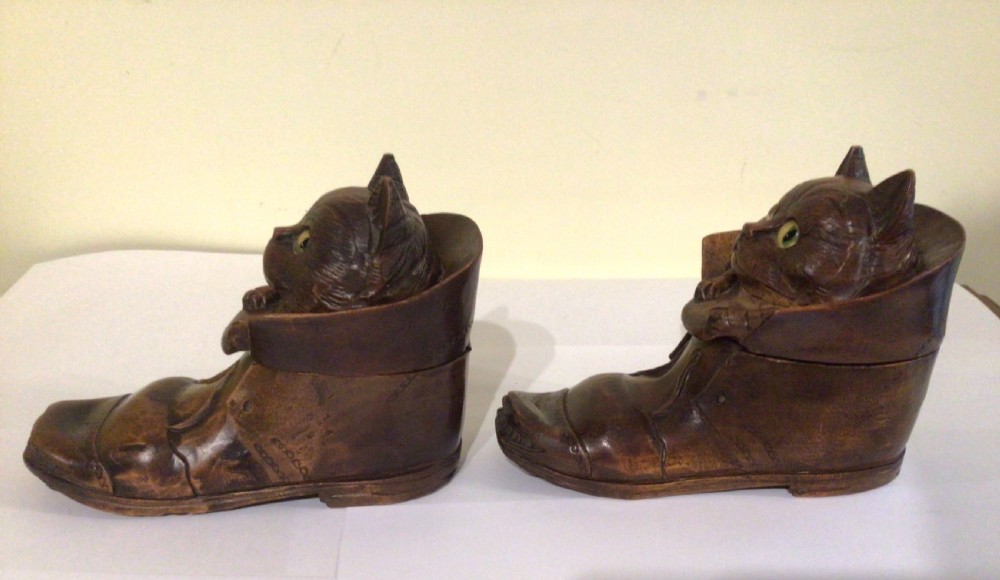 A pair of hand-carved dark brown wood inkwells shaped like cats sitting inside boots with green glass eyes. View X