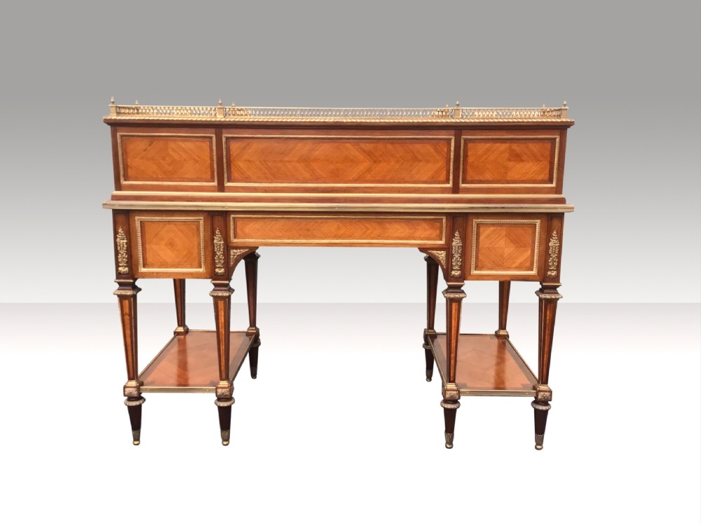 An antique French kingwood writing desk featuring a raised superstructure with small drawers, gilded brass gallery rail, leather insert, and lower side tiers supported by turned legs. View III