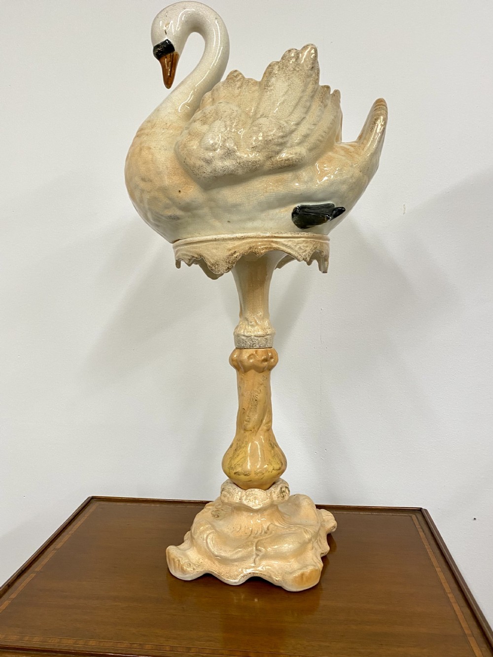 A cream glazed ceramic Victorian jardiniere formed in the shape of a swan resting atop a tall matching ornate pedestal base.
