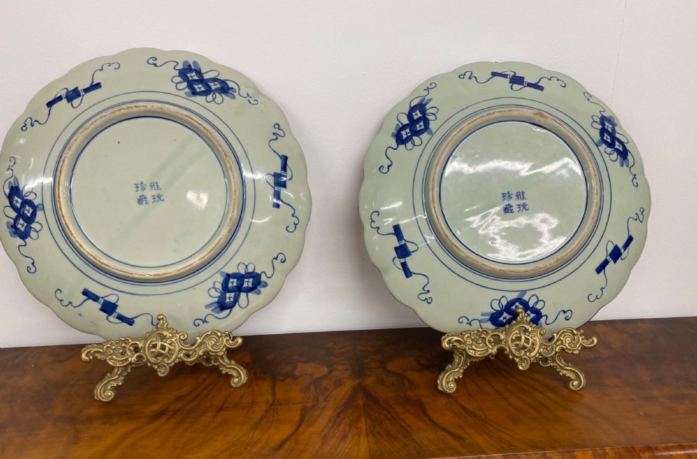 A pair of large Japanese Imari porcelain chargers featuring scalloped rims and hand-painted floral motifs in cobalt blue and iron red. View II