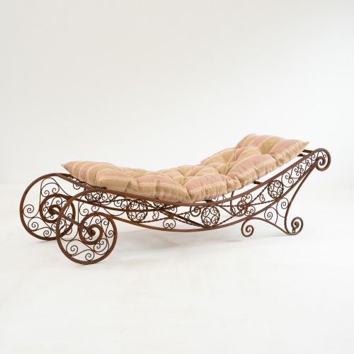 fig 1. A nineteenth-century French wrought iron garden daybed featuring scrollwork, a contoured reclining frame, and decorative front wheels with a weathered brown patina.