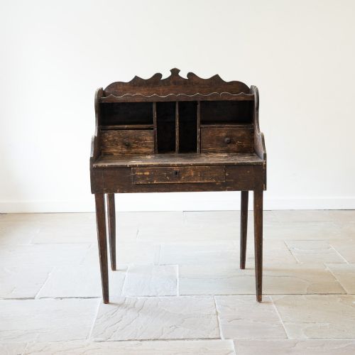 fig 1. A dark brown antique French provincial clerk desk featuring a scalloped gallery back, pigeonholes, small interior drawers, and square tapered legs.