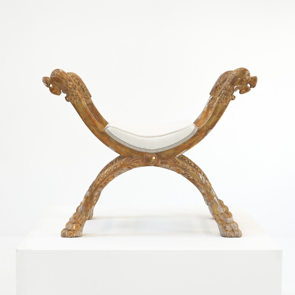 An Italian neoclassical giltwood curule stool with carved lion terminal legs and a pale cream upholstered seat. View III
