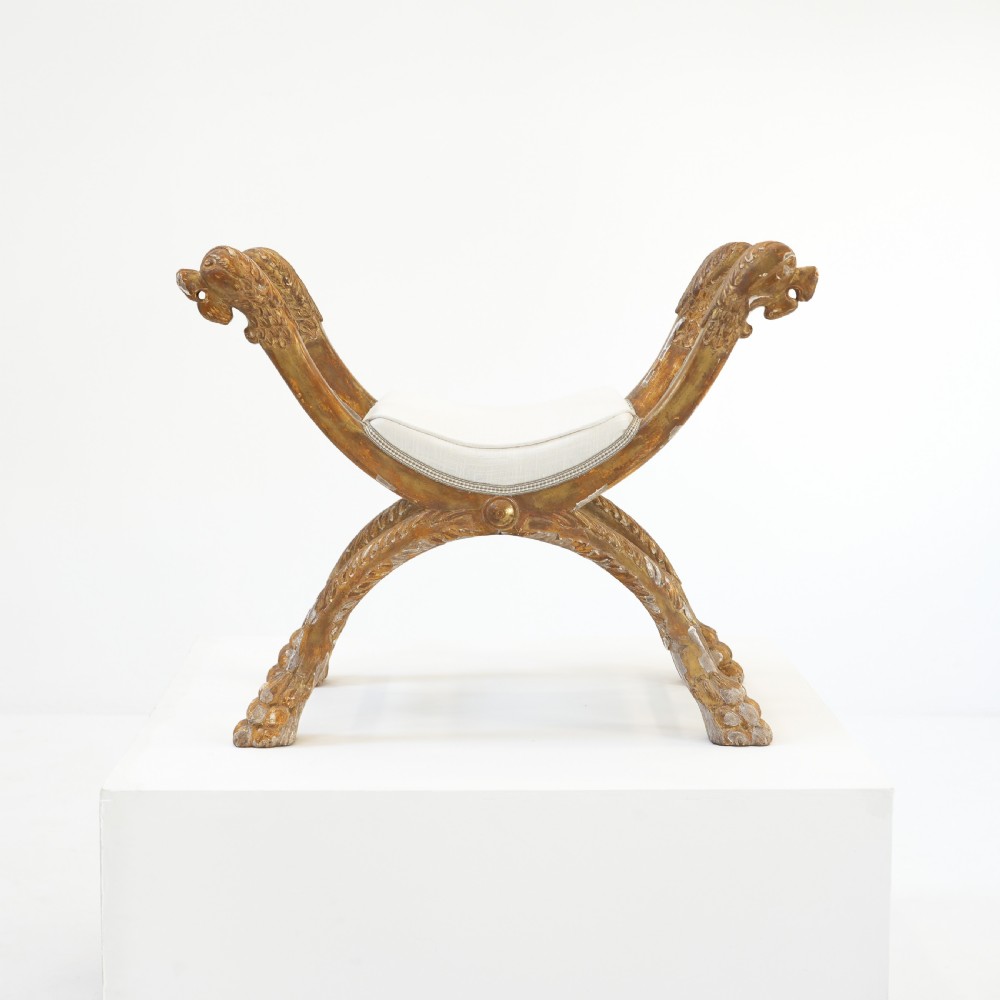 An Italian neoclassical giltwood curule stool with carved lion terminal legs and a pale cream upholstered seat. View IV