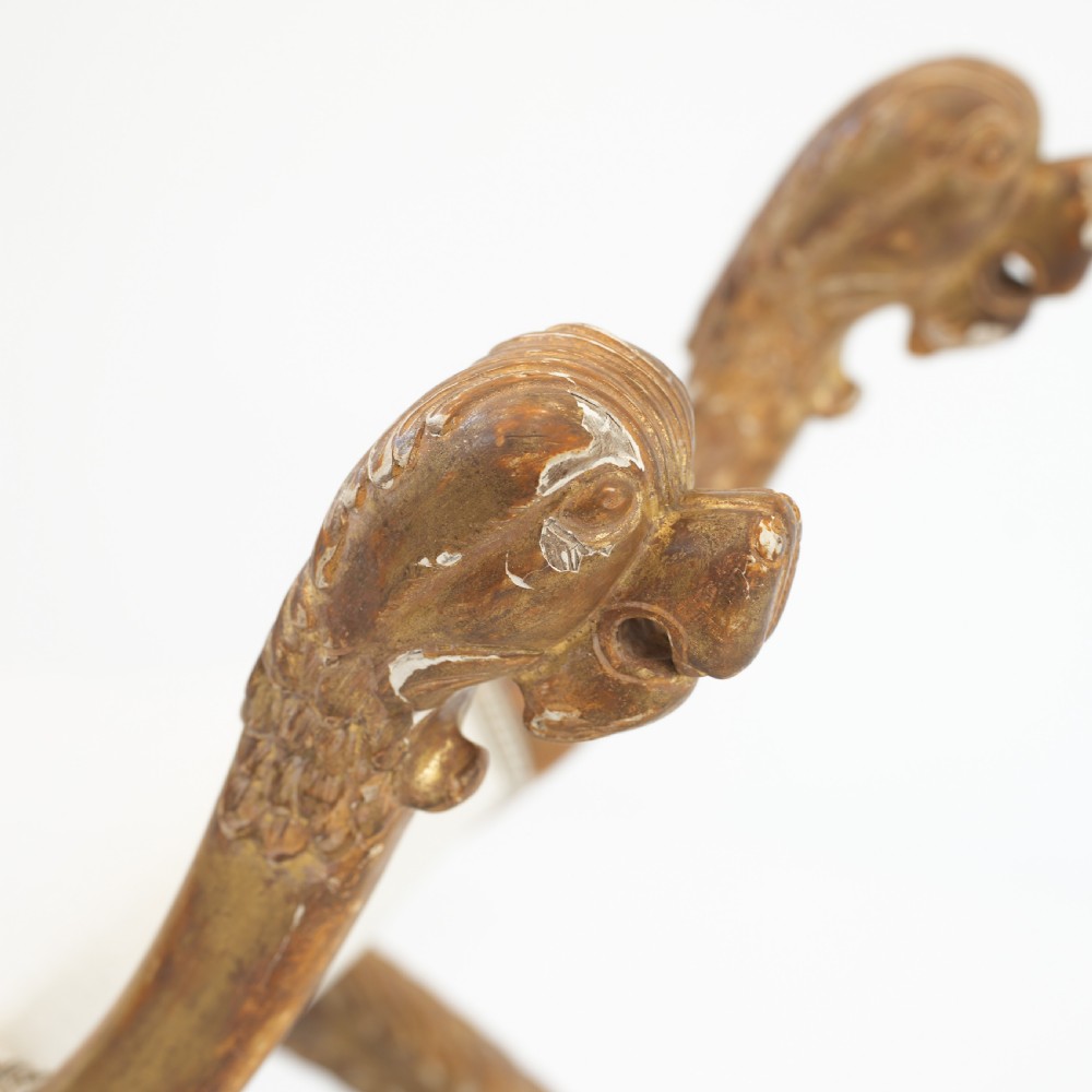 An Italian neoclassical giltwood curule stool with carved lion terminal legs and a pale cream upholstered seat. View V