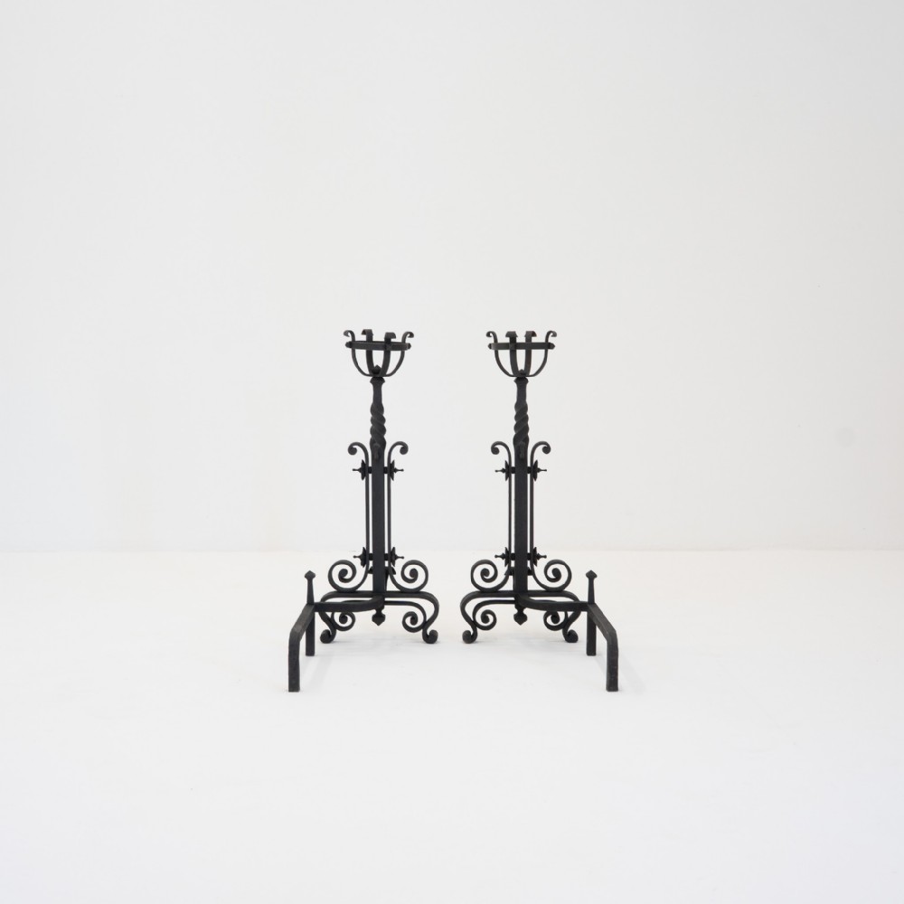 Pair of tall black wrought iron French andirons featuring forged scrollwork bases, central twisted shafts, and basket-form tops.