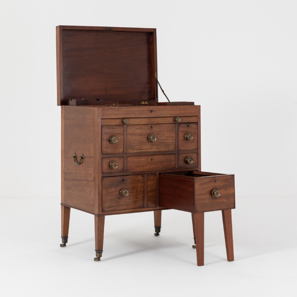 A George III mahogany travelling dressing chest featuring multiple drawer arrangements with circular brass handles, raised on square tapered legs with castors. View III