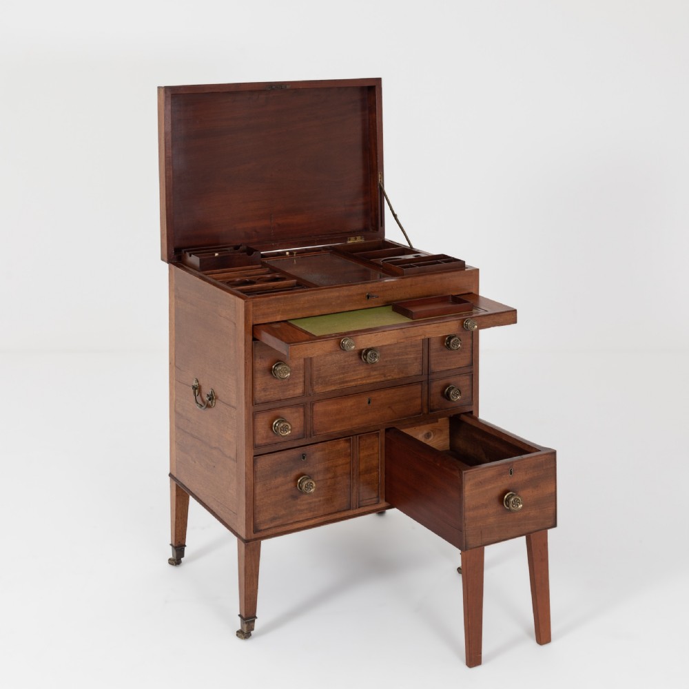 A George III mahogany travelling dressing chest featuring multiple drawer arrangements with circular brass handles, raised on square tapered legs with castors. View VI