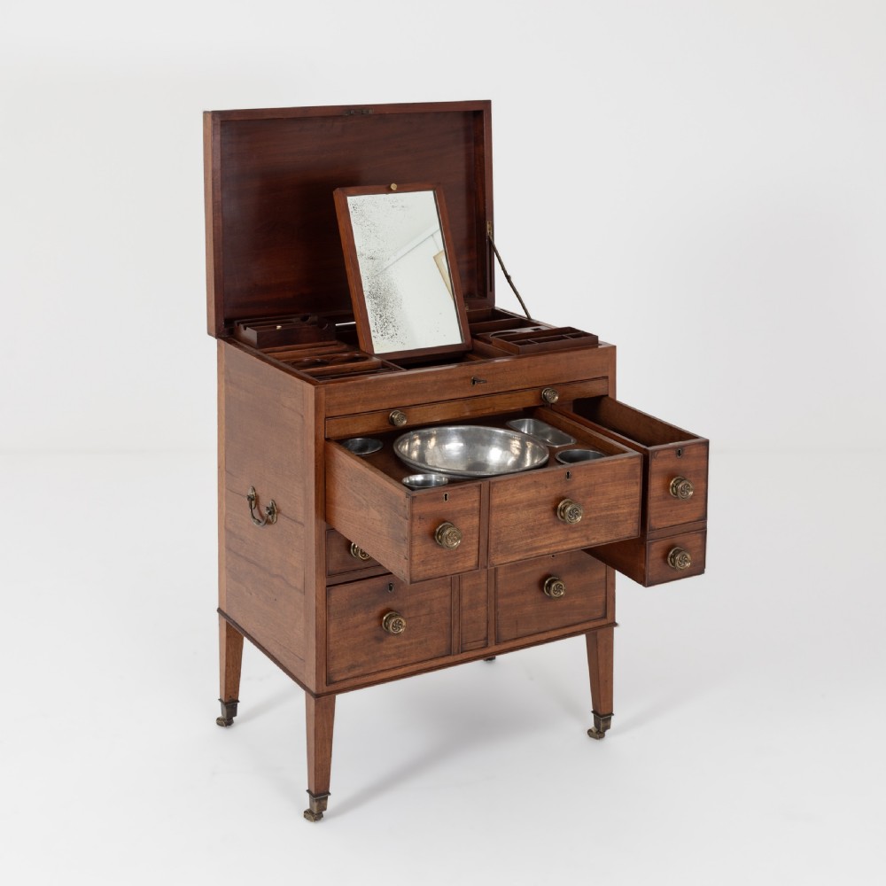 A George III mahogany travelling dressing chest featuring multiple drawer arrangements with circular brass handles, raised on square tapered legs with castors. View VII