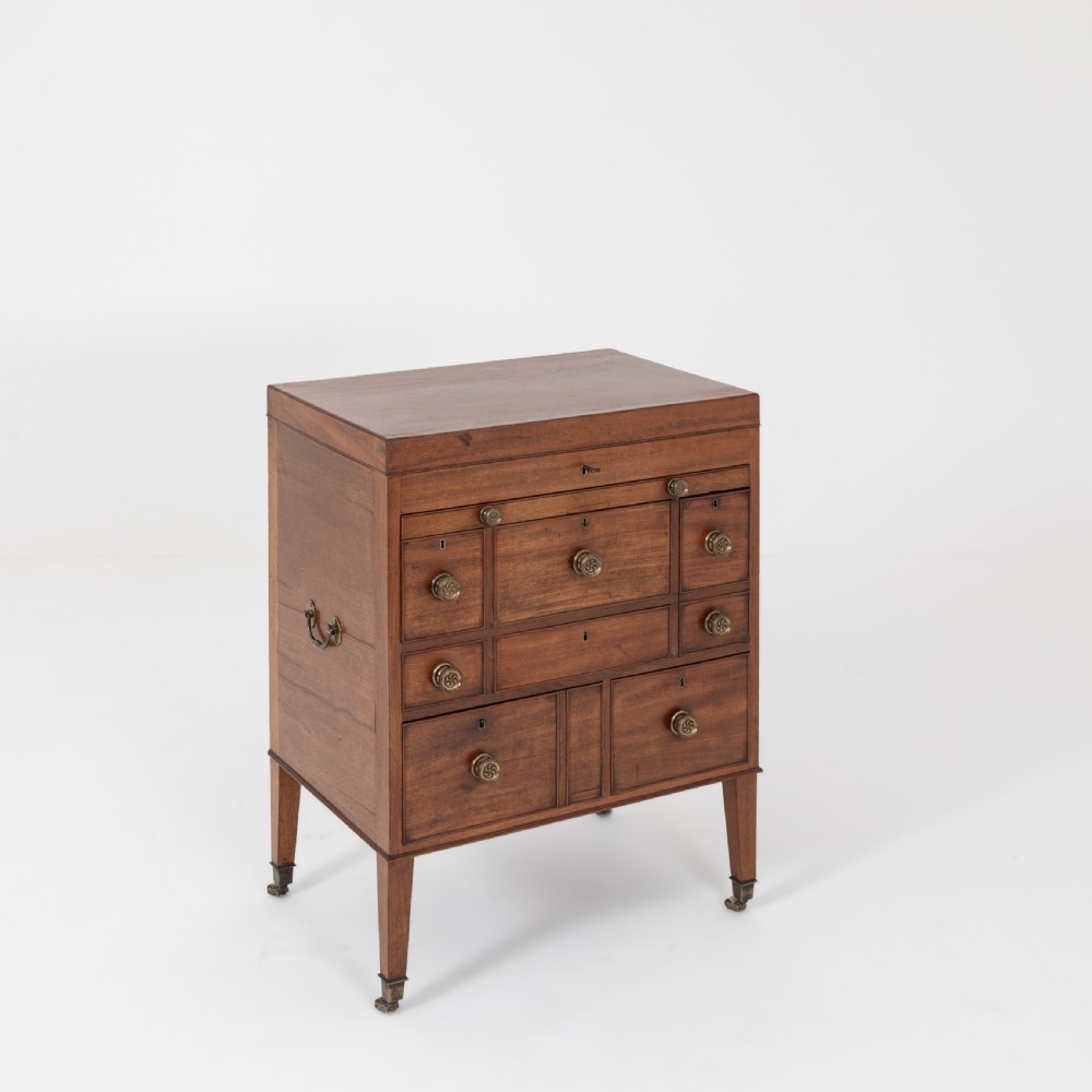 A George III mahogany travelling dressing chest featuring multiple drawer arrangements with circular brass handles, raised on square tapered legs with castors. View X