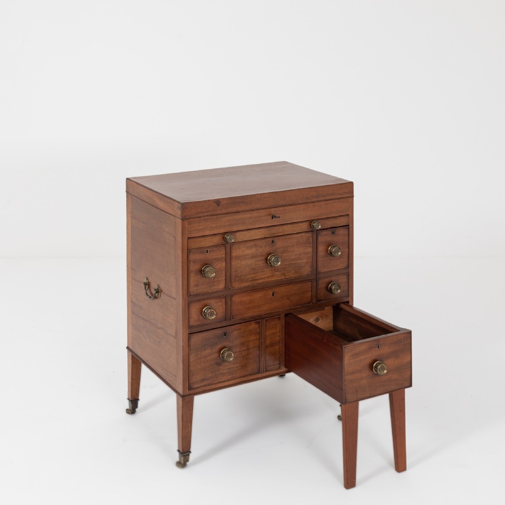 A George III mahogany travelling dressing chest featuring multiple drawer arrangements with circular brass handles, raised on square tapered legs with castors. View XI