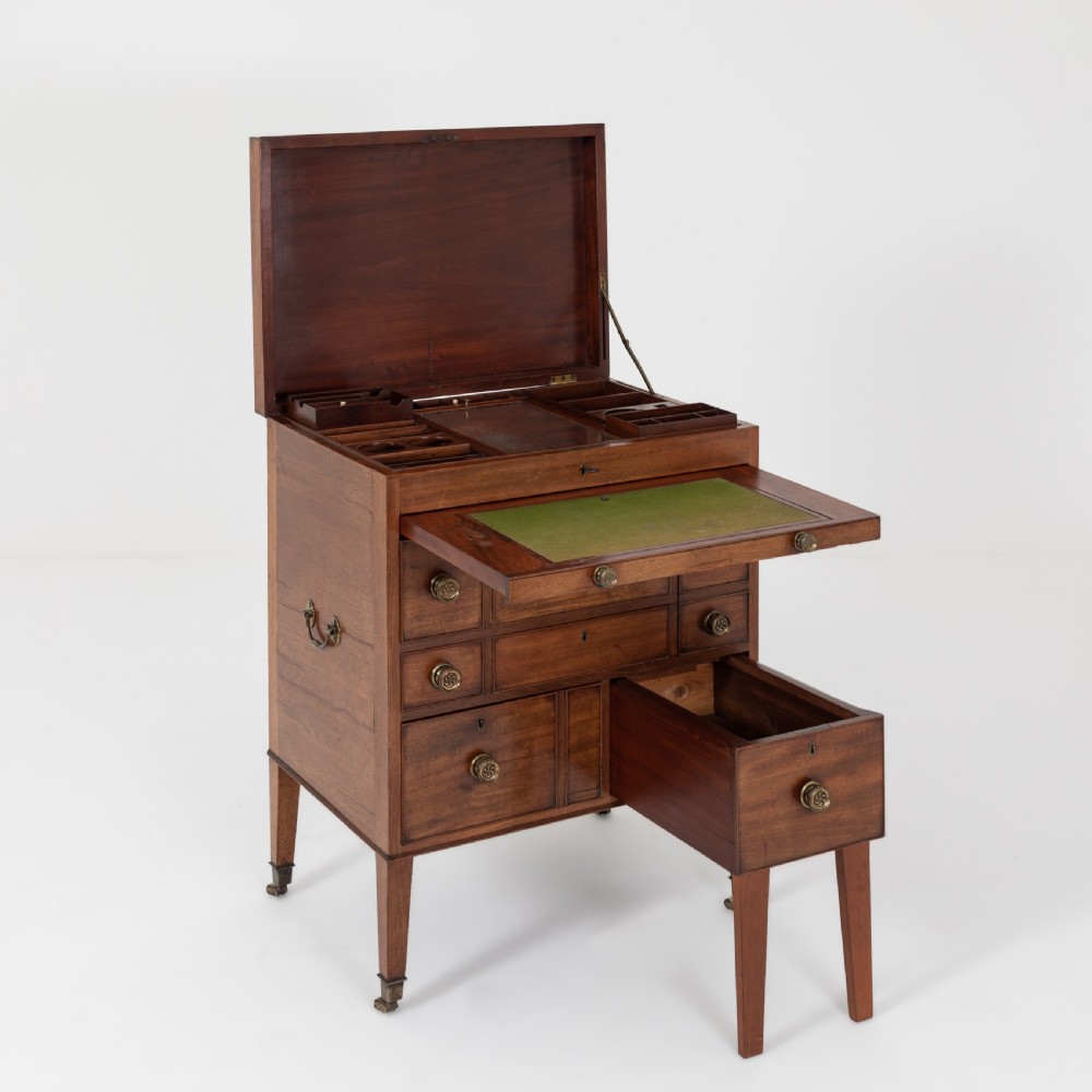 A George III mahogany travelling dressing chest featuring multiple drawer arrangements with circular brass handles, raised on square tapered legs with castors. View XIV