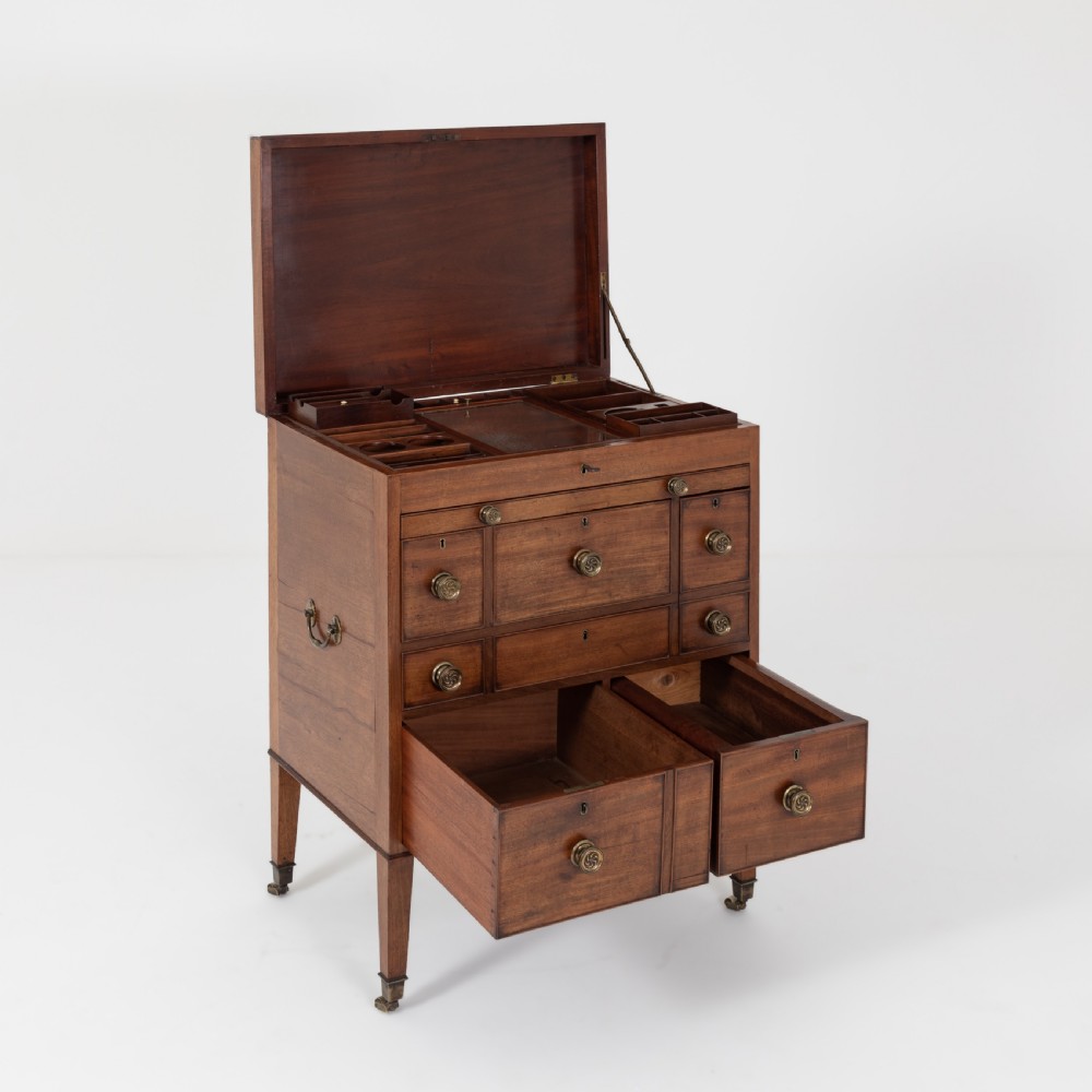 A George III mahogany travelling dressing chest featuring multiple drawer arrangements with circular brass handles, raised on square tapered legs with castors. View XVIII