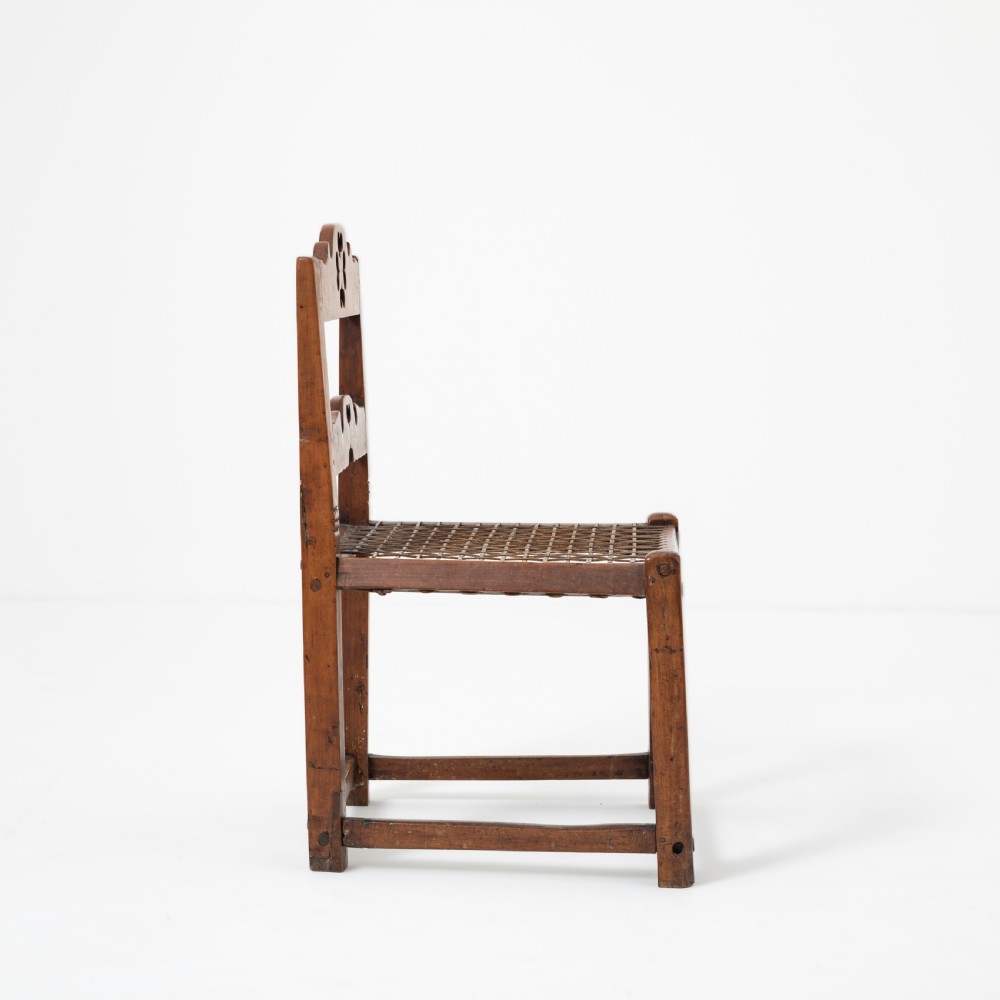 A rustic warm brown hardwood side chair featuring a carved crest rail with a pierced cutout motif and a woven seat. View III