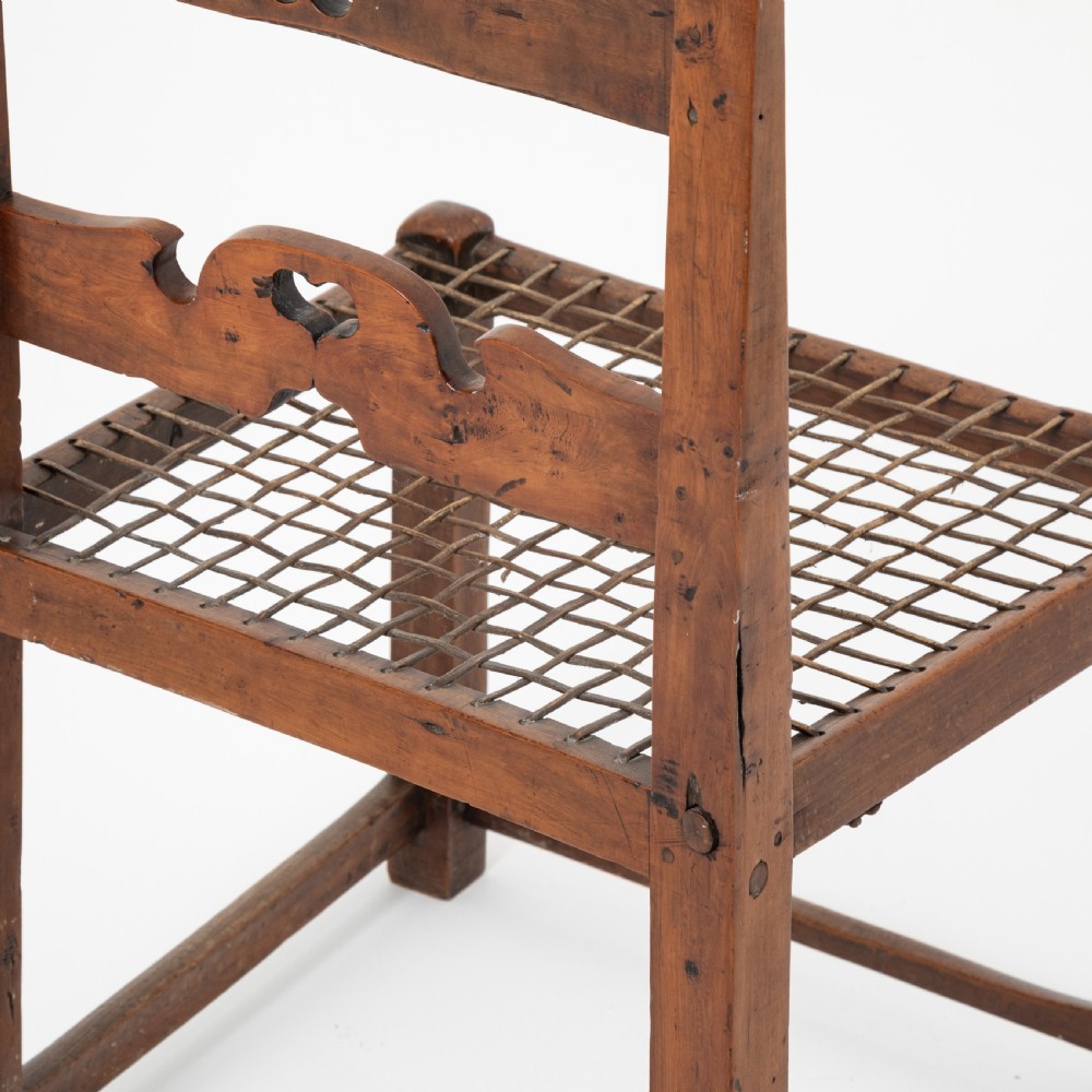 A rustic warm brown hardwood side chair featuring a carved crest rail with a pierced cutout motif and a woven seat. View VIII