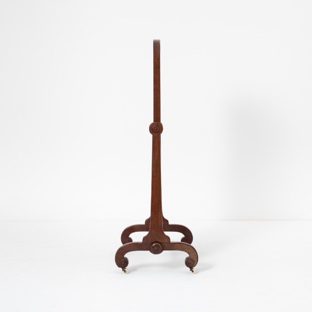 A Victorian mahogany cheval mirror featuring an arched rectangular tilting glass plate supported by turned uprights, a low stretcher, and scrolled legs on castors. View III
