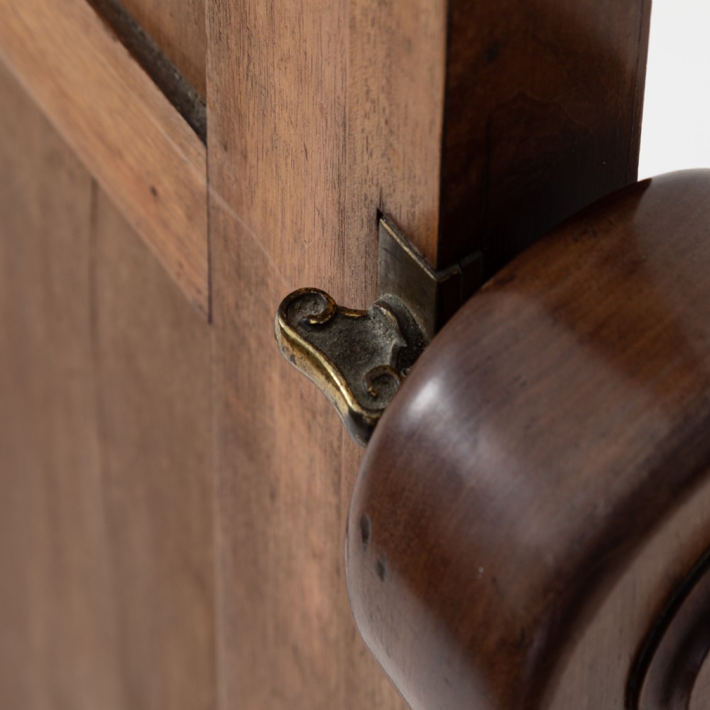 A Victorian mahogany cheval mirror featuring an arched rectangular tilting glass plate supported by turned uprights, a low stretcher, and scrolled legs on castors. View VI
