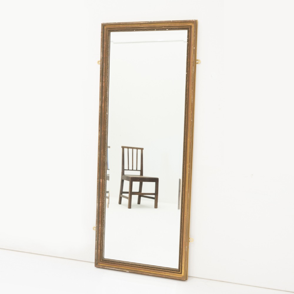 A tall rectangular wall mirror featuring a narrow giltwood frame with subtle moulded edge detailing.